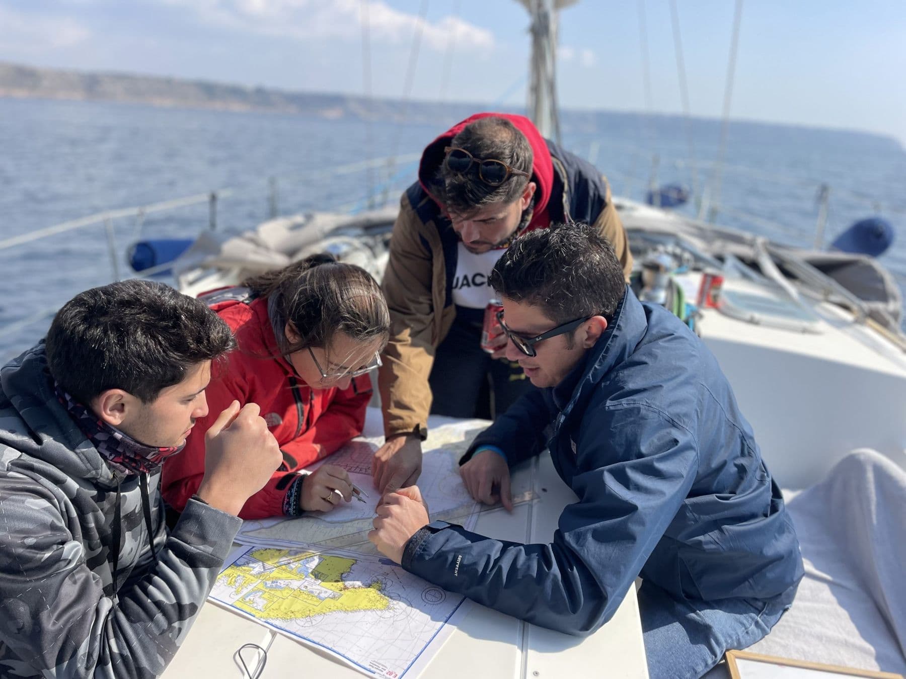 Alumnos de la academia con la carta náutica a bordo de un velero